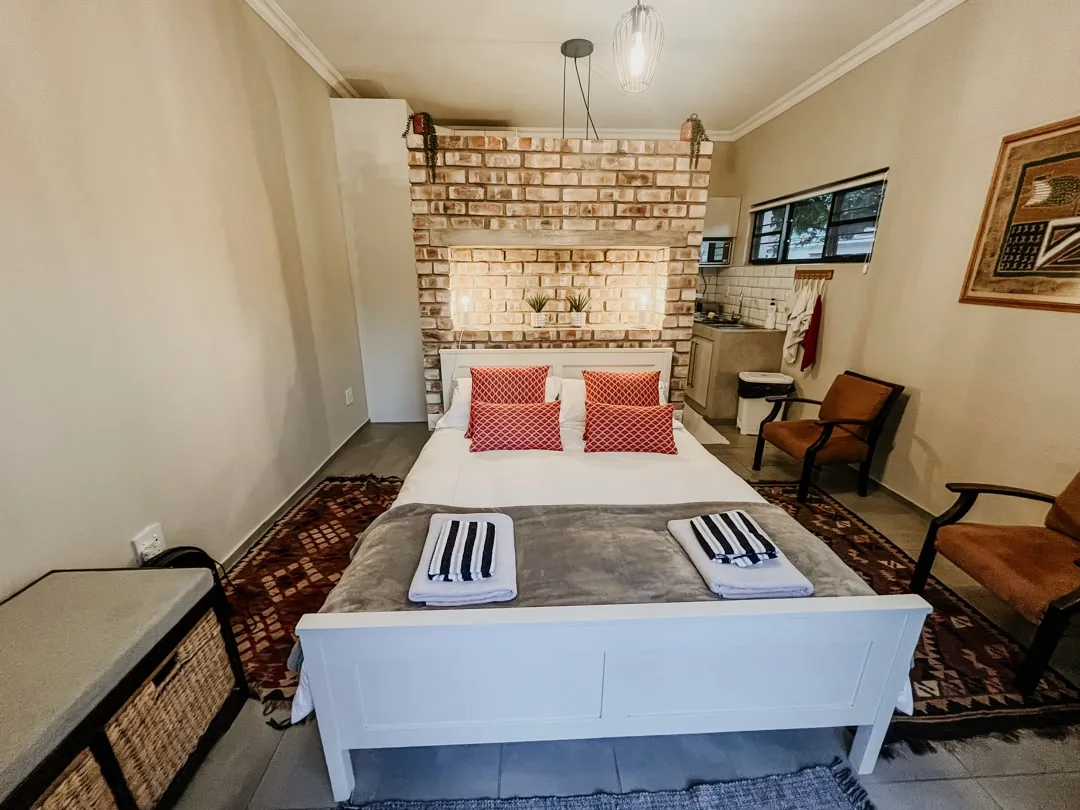 Lion self-catering bedroom with queen bed and exposed brick wall